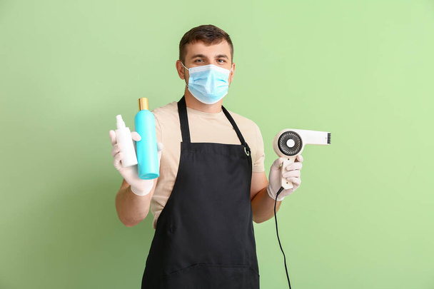 Мужчина парикмахер носит медицинскую маску на цветном фоне. Эпидемия коронавируса - Фото, изображение