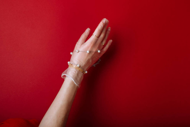 Moda arte mano mujer en el guante de protección contra COVID-19 con joyas aisladas sobre fondo rojo. - Foto, imagen