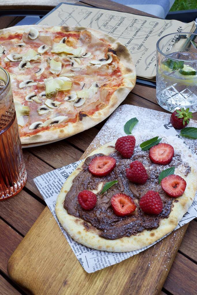 A vertical high angle shot of delicious pizza and dessert on a table - Fotó, kép