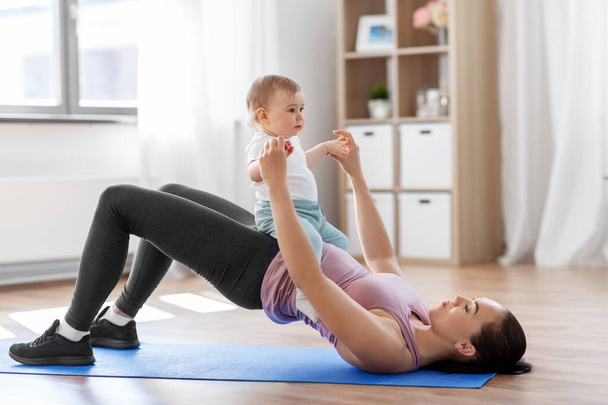 mother with little baby exercising at home - Foto, Imagen