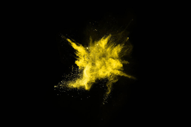 Gefrierbewegung der gelben Staubexplosion isoliert auf schwarzem Hintergrund. - Foto, Bild