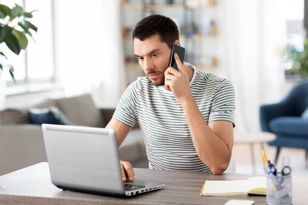 man with laptop calling on phone at home office - Φωτογραφία, εικόνα
