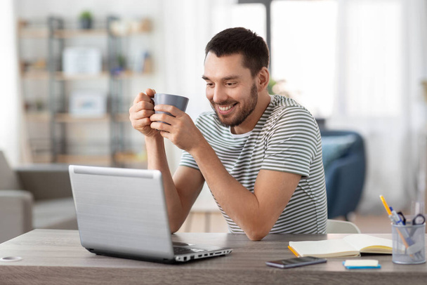 man with laptop drinking coffee at home office - Foto, immagini