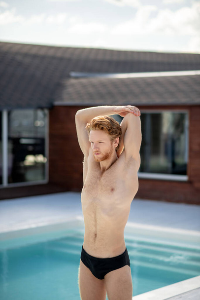 Young adult man standing near the pool. - Photo, image