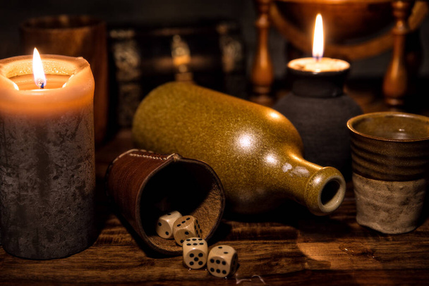 medieval table with candles, a old bottle, a mug and wooden dice, concept game party - Fotoğraf, Görsel