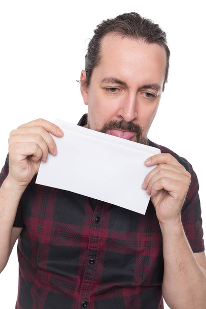 caucasian man holding and licking a white envelope, isolated on white - Foto, immagini