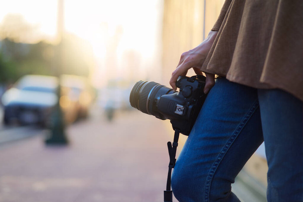Acercamiento Fotógrafo de pie y sosteniendo la cámara a la mano con la luz del sol, fotógrafo y concepto de cámara
 - Foto, imagen