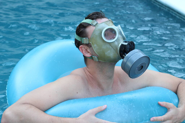 retrato de cerca del joven guapo en máscara protectora de gas en la piscina durante el bloqueo del coronavirus
 - Foto, imagen