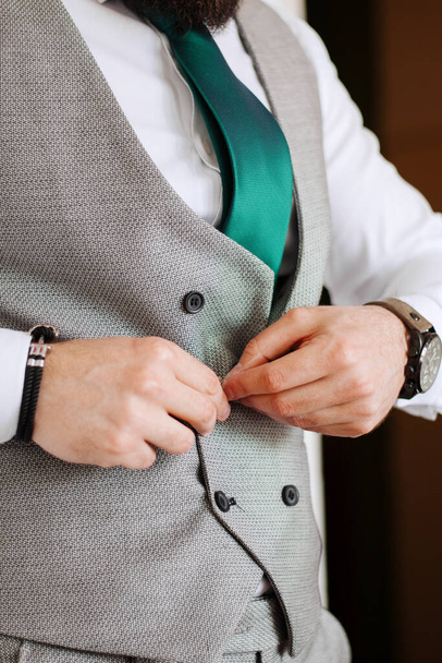 Manos masculinas abotonando chaleco de traje gris moderno. Aspecto muy elegante
.  - Foto, imagen