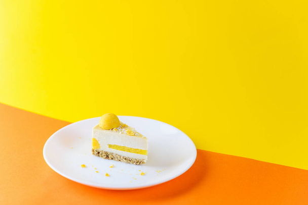 A slice of raw cashew cake with mango marmalade and praline on a yellow-orange background. Sugar, lactose, gluten free. - Photo, image