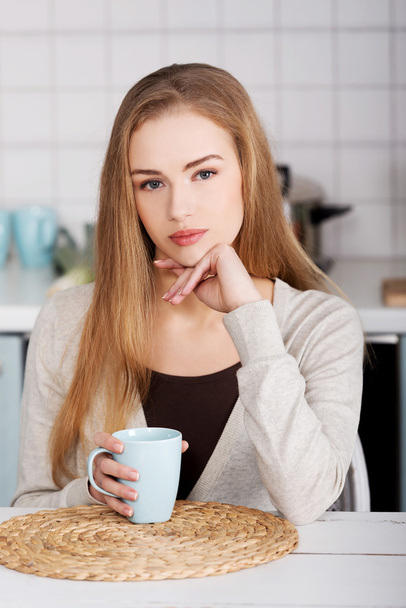 Beautiful caucasian woman is sitting by table with cup of coffee - 写真・画像