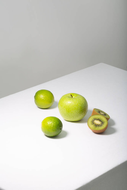 Fresh green fruits on white table, vertical orientation - Photo, Image