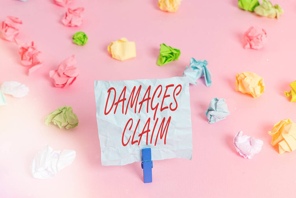 Writing note showing Damages Claim. Business photo showcasing seeks to repair the damages or liability of the victim party Colored crumpled papers empty reminder pink floor background clothespin. - Photo, Image