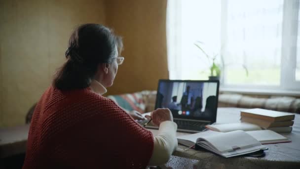 koulutus verkossa, vanha nainen opiskelee verkossa avulla modernin teknologian istuu kotona pöydän kannettava tietokone - Materiaali, video