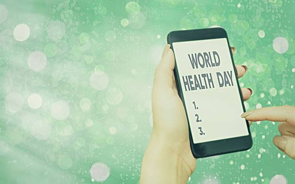 Dünya Sağlık Günü 'nü gösteren bir mesaj. Kavramsal fotoğraf küresel sağlık farkındalığı günü her yıl 7 Nisan 'da renkli bokeh arka plan altında beyaz ekranlı modern cihazlarla kutlanır.. - Fotoğraf, Görsel