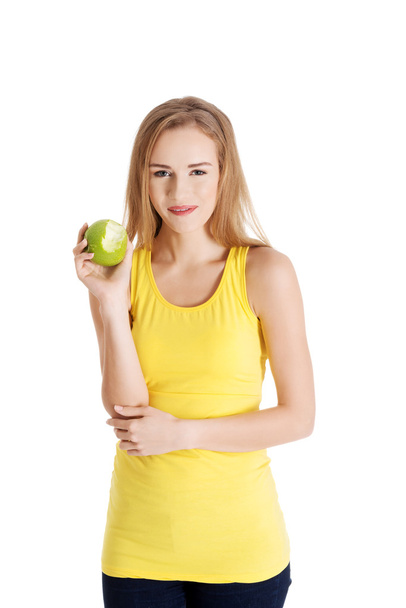 Hermosa mujer caucásica causal sosteniendo manzana verde fresca con mordida faltante
 - Foto, Imagen