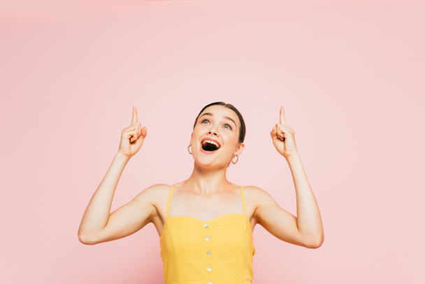 excited brunette young woman pointing with fingers up isolated on pink - Fotografie, Obrázek