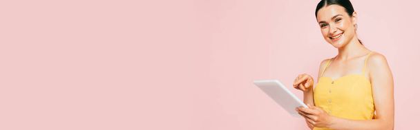 brunette young woman using digital tablet isolated on pink, panoramic shot - Foto, imagen