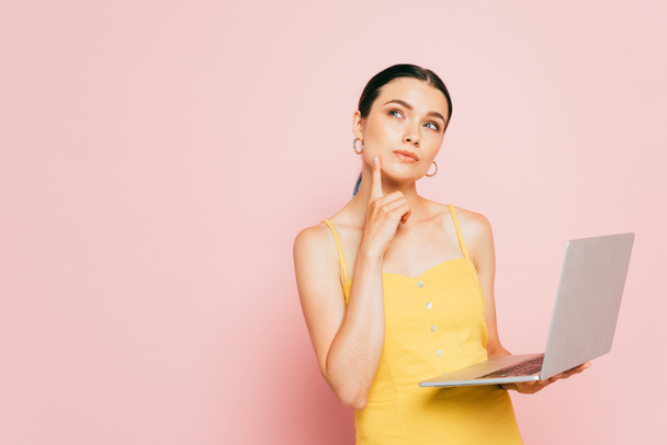 zamyślony brunetka młoda kobieta za pomocą laptopa na różowy - Zdjęcie, obraz