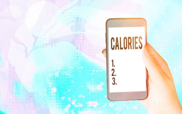 Píšou slova o kaloriích. Obchodní koncept pro množství potravin, které mají hodnotu energie jedné velké kalorie Moderní gadgets s bílým displejem obrazovky pod barevné pozadí bokeh. - Fotografie, Obrázek