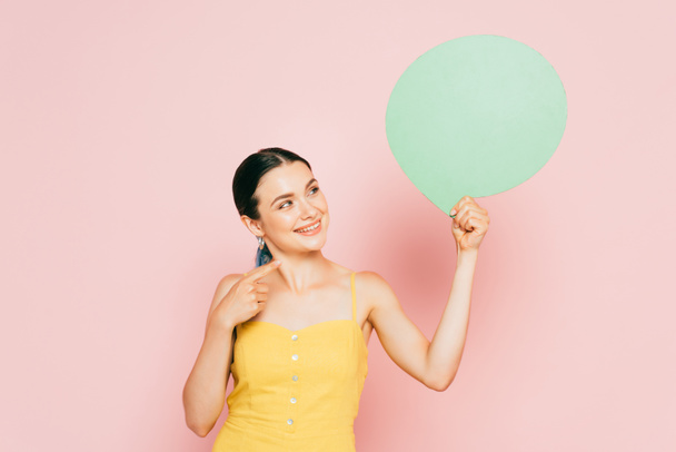 brunette young woman with green blank speech bubble on pink - 写真・画像