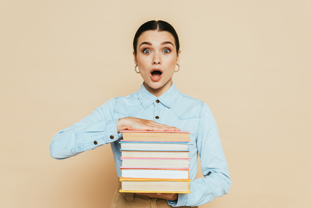 shocked student in denim shirt with books on beige - Fotografie, Obrázek