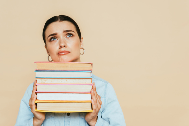 sad student in denim shirt with books isolated on beige - Foto, imagen