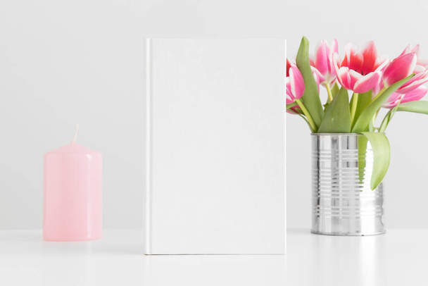 Mockup libro bianco con tulipani rosa in una pentola e candela su un tavolo bianco. - Foto, immagini