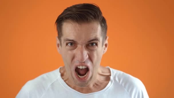 Retrato de un hombre gritando sobre un fondo naranja. fanático de los deportes se regocija por ganar partido de apuestas equipo deportivo - Metraje, vídeo