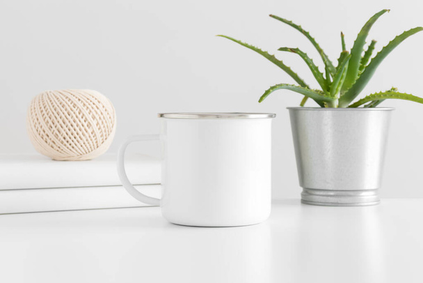 Enamel mug mockup with workspace accessories and a succulent plant on a white table. - Foto, afbeelding