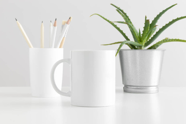 Taza maqueta con accesorios de espacio de trabajo y una planta suculenta sobre una mesa blanca
. - Foto, imagen