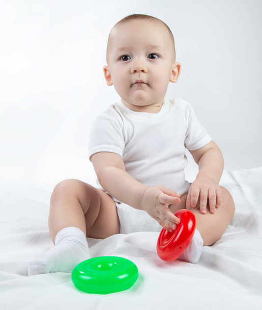 Foto de un bebé sentado de nueve meses con juguetes brillantes
 - Foto, Imagen