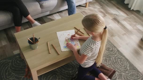 Μικρό κορίτσι ζωγραφίζει ευτυχισμένη οικογενειακή εικόνα - Πλάνα, βίντεο