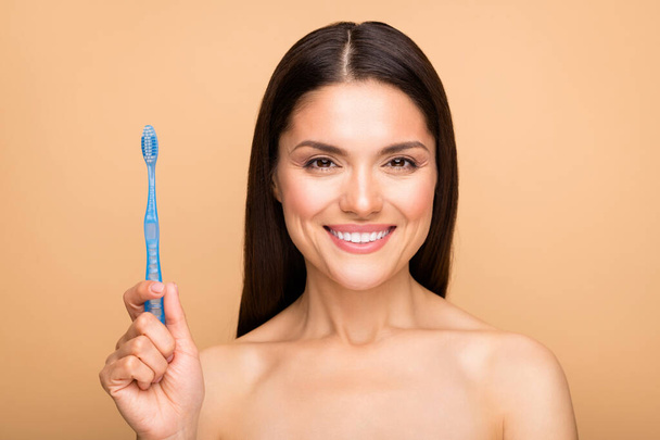 Close-up portrait of her she nice-looking attractive lovely charming cheerful cheery woman holding in hand toothbrush isolated over beige pastel color background - Foto, Bild