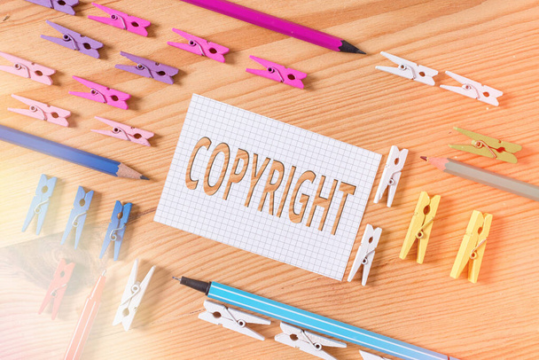 Conceptual hand writing showing Copyright. Business photo text exclusive legal right to reproduce, publish, sell, or distribute Colored crumpled papers wooden floor background clothespin. - Photo, Image