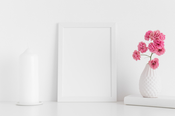 White frame mockup with pink roses in a vase and candle on a white table.Portrait orientation. - Photo, Image