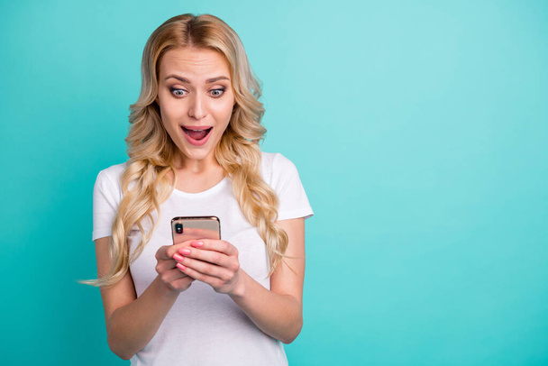Portrait of astonished positive girl use cellphone read followers social media notification news impressed scream wear good look style outfit isolated turquoise color background - Foto, afbeelding