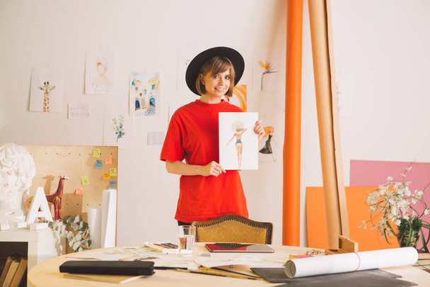 Kaunis hymyilevä tyttö taiteilija hattu seisoo piirustus art studio. Valokuvaus mainos taidekursseja tai blogi - Valokuva, kuva