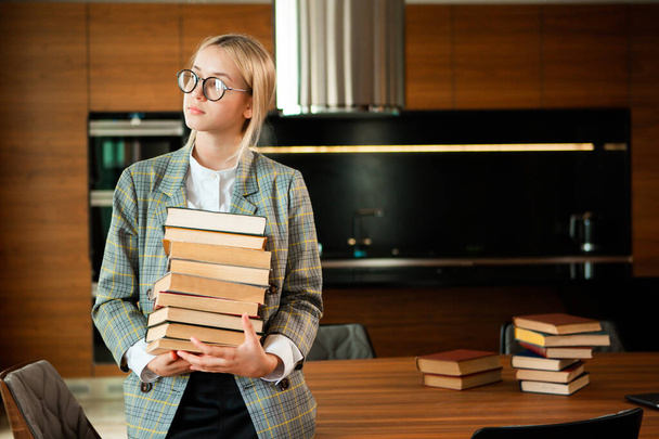 Cute teen girl student in casual clothes and glasses stands with books. Back to school. Exam preparation - Фото, изображение