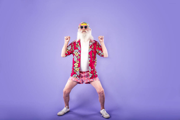 Fashionable grandfather posing with funny clothes. Senior man portraits on colored background - Foto, immagini