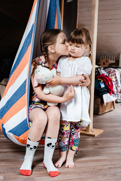 Children sit on a hammock in the room, playing and talking. Brown eyes. The concept of children's style and fashion. Summer holidays. Carefree childhood. Toning. - Fotoğraf, Görsel