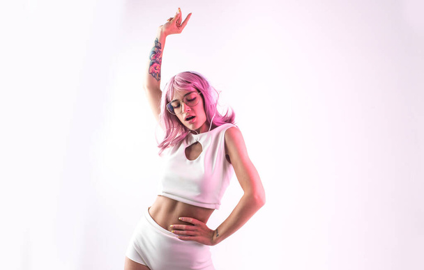 Young woman with pink hair dancing and having fun. Colored gel portraits with futuristic outfit - Fotó, kép