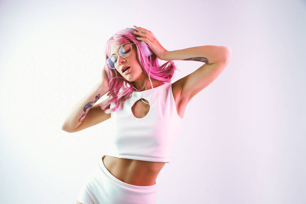 Young woman with pink hair dancing and having fun. Colored gel portraits with futuristic outfit - Foto, immagini