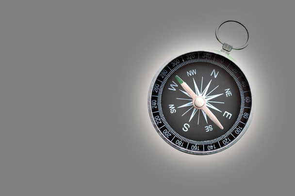 Круглый компас на абстрактном сером фоне как символ туризма с компасом, путешествия с компасом и активного отдыха с компасом - Фото, изображение
