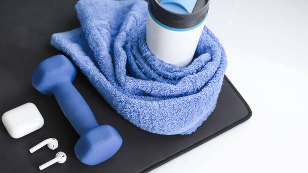 Sports background with blue accent dumbbell, glass, towel, elepsoid. Sports activities. Sports at home, attributes for sports. Active lifestyle. - Foto, immagini