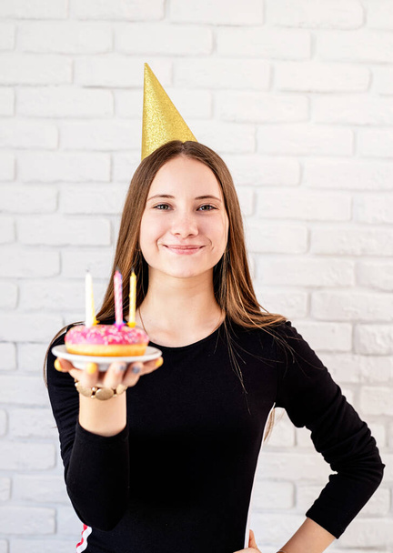 Verjaardagsfeestje. gelukkig jong vrouw houden een verjaardag donut met kaarsen - Foto, afbeelding