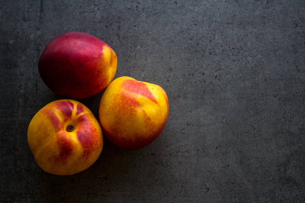 Fresh nectarines on a table. Juicy summer fruits close up photo. Dark grey background with copy space. Healthy eating concept.  - Photo, Image