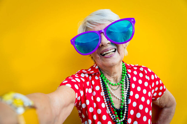 Happy grandmother posing on colored backgrounds. Woman having fun and celebrating - Fotografie, Obrázek