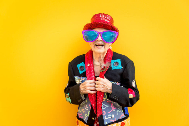 Boldog nagymama pózol színes háttérrel. Nő szórakozás és ünneplés - Fotó, kép