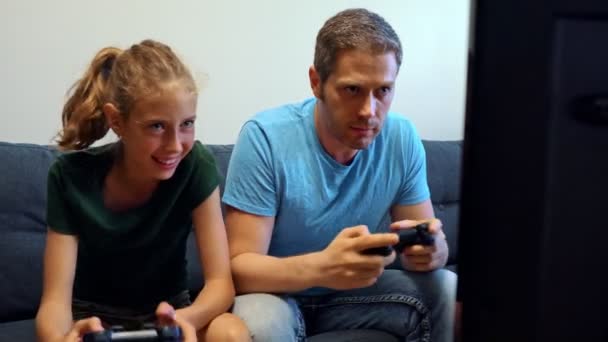 Ο μπαμπάς και η κόρη του παίζουν παιχνίδια κονσόλας με ασύρματα joystick. - Πλάνα, βίντεο
